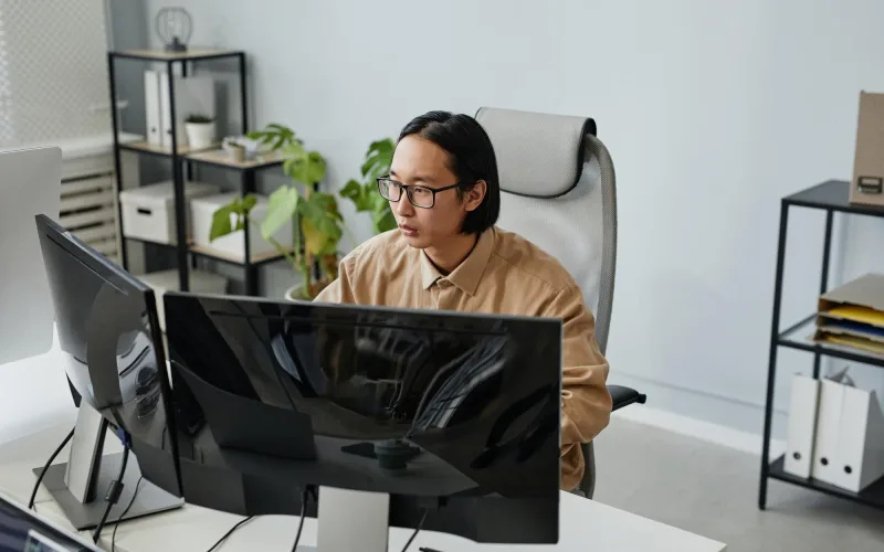 An engineer focused on monitoring a production dashboard on a large monitor